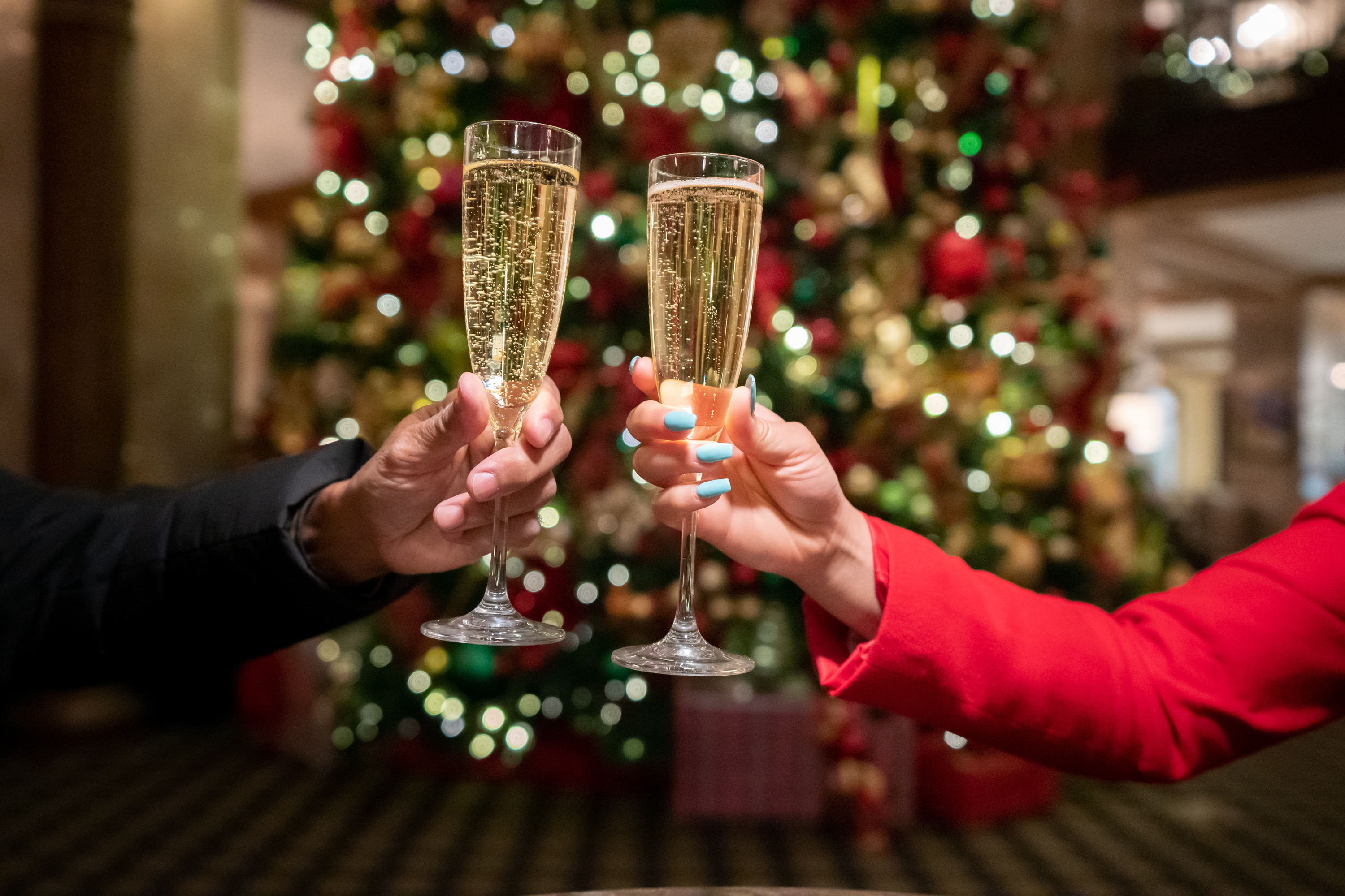 people toasting champagne in front of christmas tree