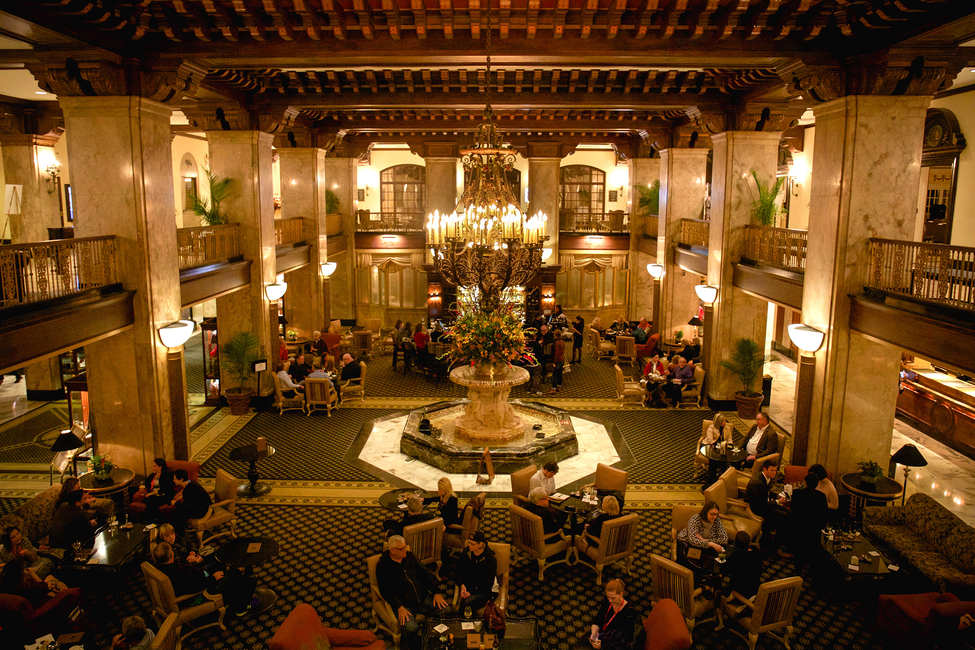 People at tables inside the lobby at The Peabody Memphis, with the fountain in the center of the image.
