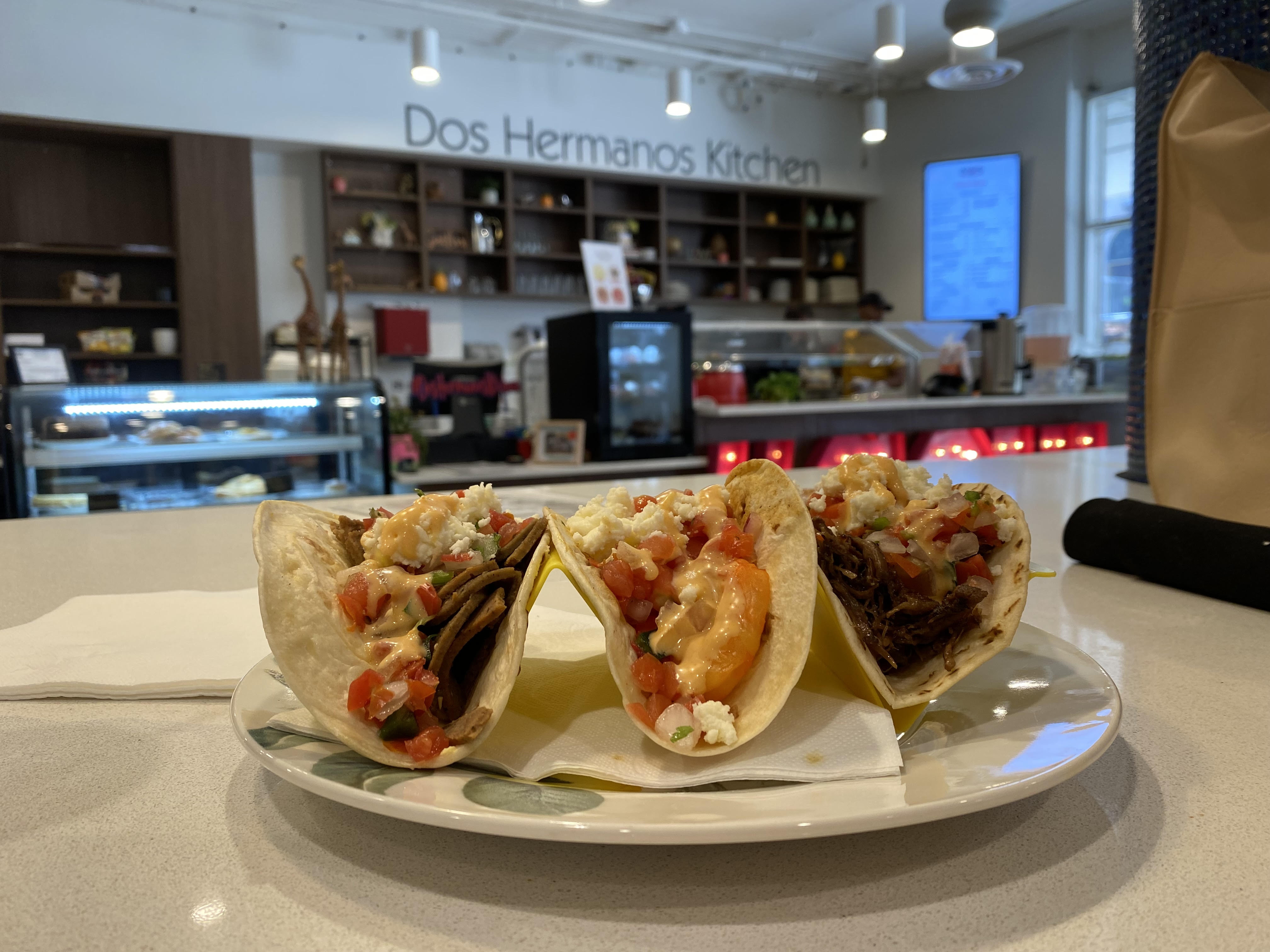 three tacos on plate in front of dos Hermanos kitchen 