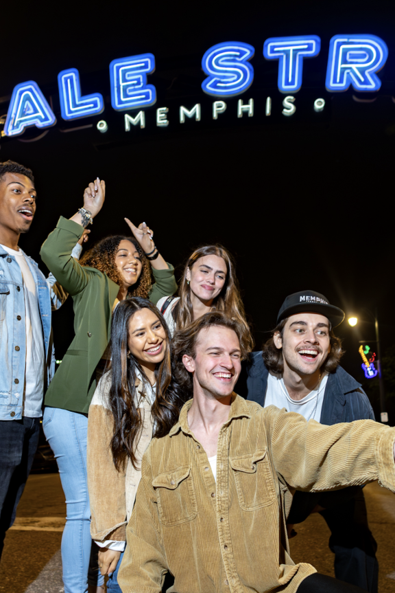 group of friends pose in front of beale street sign