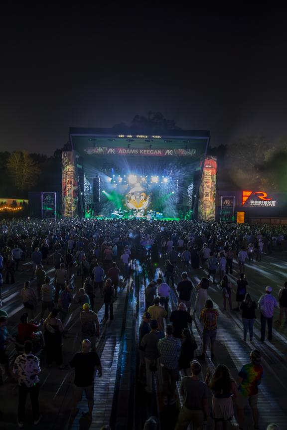 widest from far back showing music stage lit up at night and large crowd