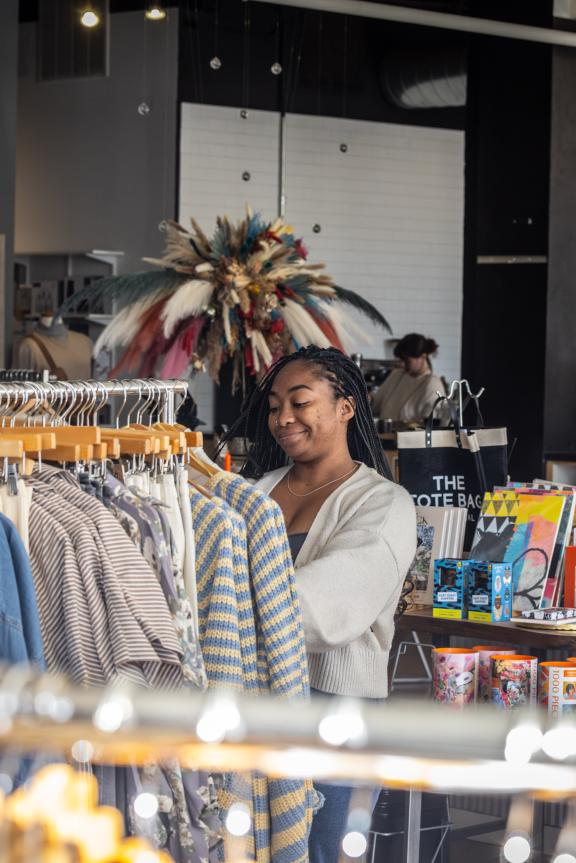 Girl shopping and sorting through clothing racks at a store