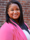 Tyra Johnson in a Pink blazer against a brick wall