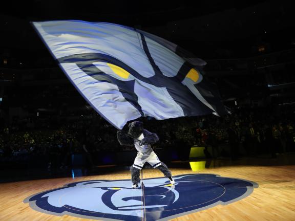 Grizz waving Memphis Grizzlies flag at an NBA basketball game.