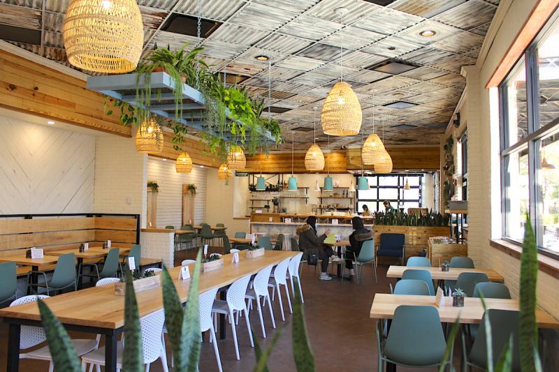 restaurant interior with warm lighting, long tables, hanging woven lamps