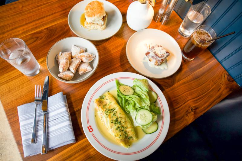 table with omelet, chicken biscuit, and brunch items at Bishop restaurant