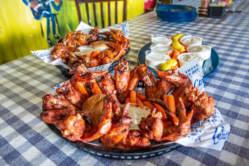big platters of chicken wings on a blue checkered tablecloth