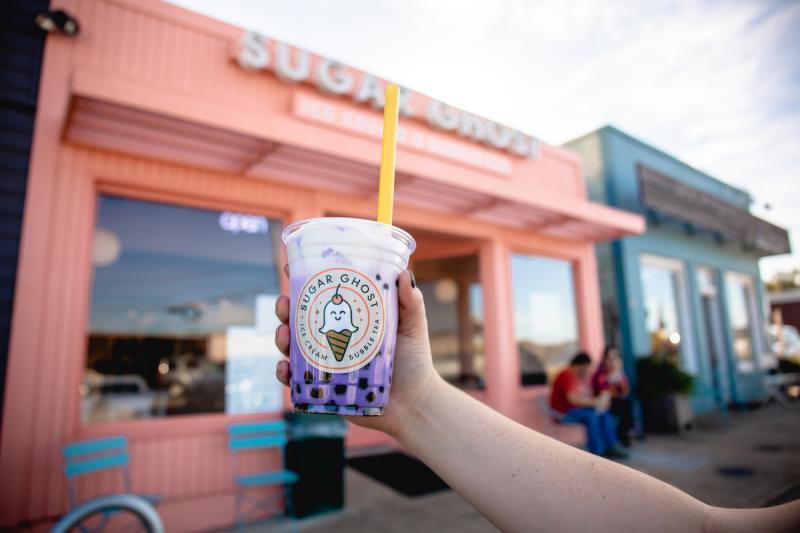 purple milk tea with sugar ghost label in front of pink storefront