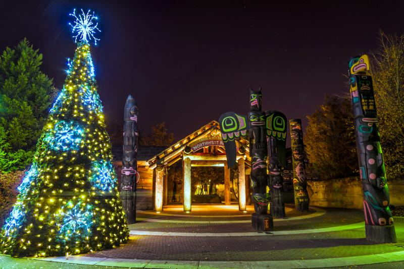 holiday tree lit up in Northwest Passage with totem poles at the Memphis Zoo