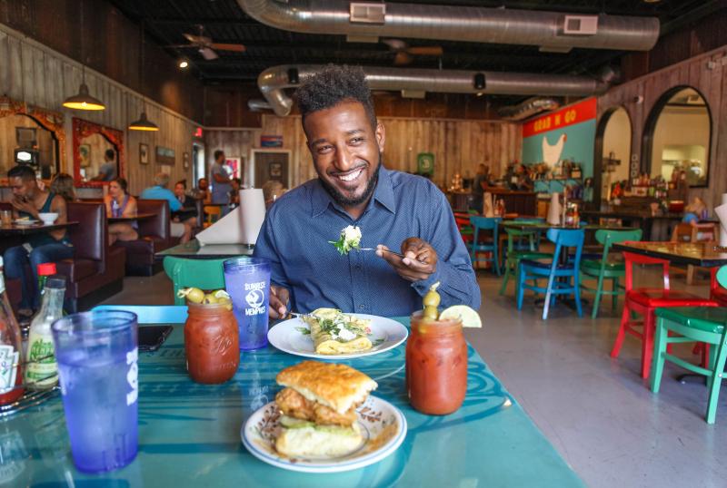 man smiles eating omelette with Bloody Mary at sunrise memphis
