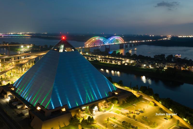 the Bass Pro Pyramid glows at night with the mighty lights bridge behind