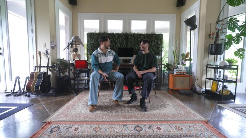 two filipino men sitting next to each other, facing one another as they talk