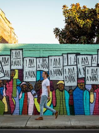 man walks in front of I am a man mural