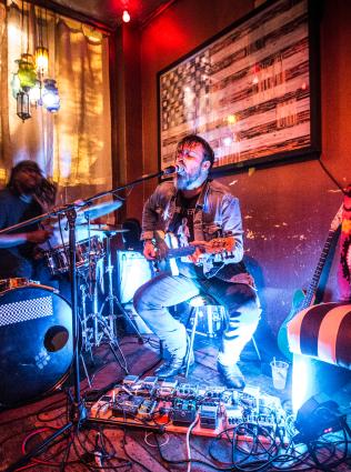 man plays guitar at bar dkdc
