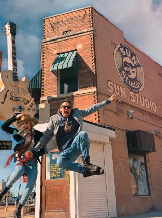 Two tourists jump up in the air outside of Memphis' Sun Studio