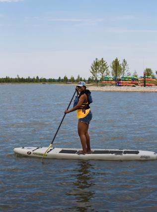 woman paddle boards on lake at Shelby farms park