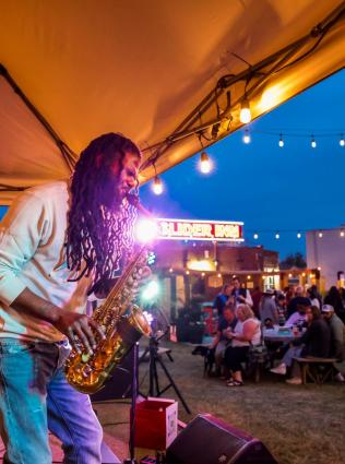 Saxophone player performing on stage in a courtyard, photo by Alex Shansky