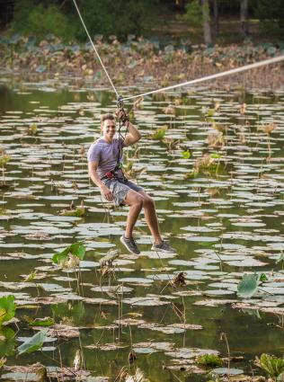 Someone zip lining over a body of water with Go Ape Adventure at Shelby Farms Park.