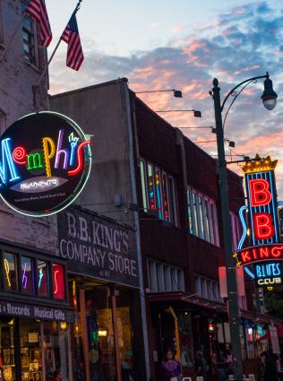 Neon "Memphis" and "B.B. King's Blues Club" signs along Beale Street at sunset..