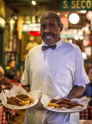 Waiter carrying plates of World Famous Rendezvous barbecue.