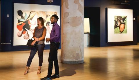 Two people stand looking at pieces in Crosstown Concourse art gallery.