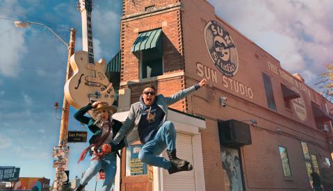two people jump in the air in front of sun studio