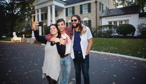 people pose for photo in front of graceland