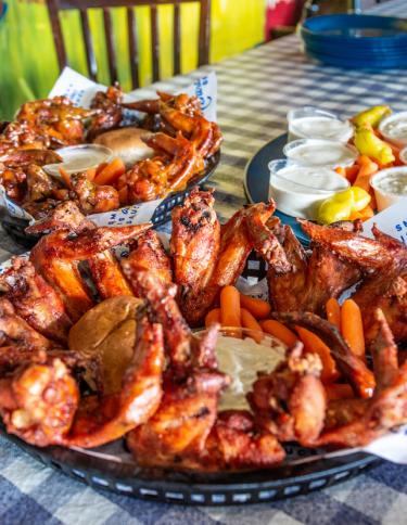 big platters of chicken wings on a blue checkered tablecloth