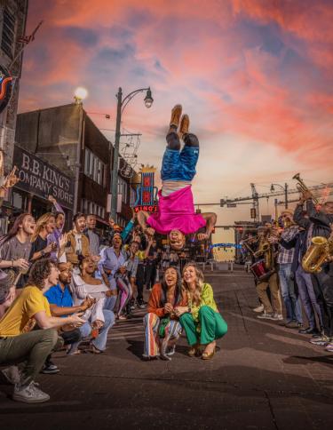 A Beale Street Flipper performs acrobatics over a crowd of onlookers on Beale Street in Memphis, Tennessee, at sunset..