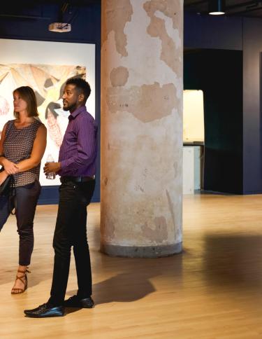 two people stand in Crosstown Concourse art gallery looking at pieces