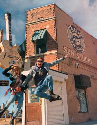 two people jump in the air in front of sun studio