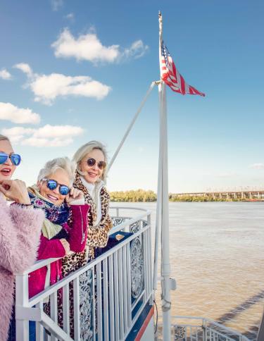 three women pose on dock of boat