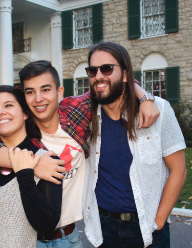 three people pose for photo in front of Graceland