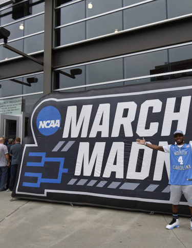 man stands in front of march madness sign