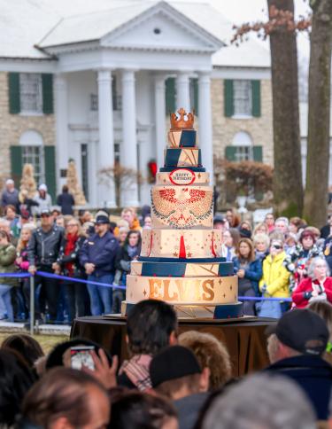 elvis birthday cake on display in front of crowd and Graceland mansion