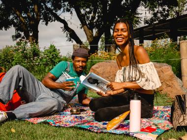 A couple reads and enjoys a picnic at River Garden Park Summer