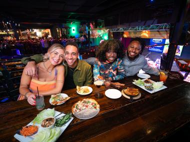 four friends smile for food at dinner
