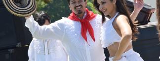 man in white with red scarf holding traditional Colombian hat, woman dancer next to him