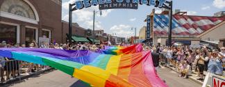 massive pride flag being held up during pride parade on beale street