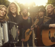 five men and one woman holding various gutars, accordions, and washboards smiling into the camera