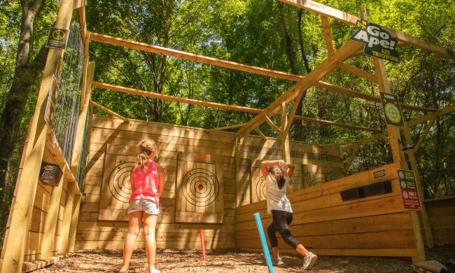 Two girls outdoor axe throwing with Go Ape at Shelby Farms Park.