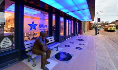 view of Blues Hall of Fame exterior with blue lights and Little Milton Statue