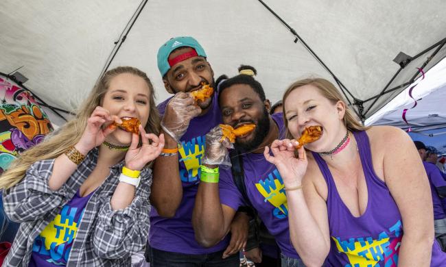 people eating chicken wings in a tent at a festival