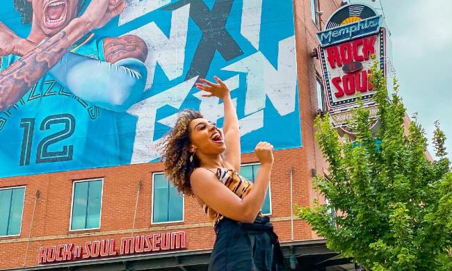 A traveler stands in front of a colorful mural outside the Rock 'n' Soul Museum.