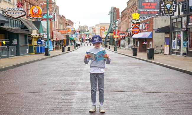 Kid reads a field trip guide on Beale Street.