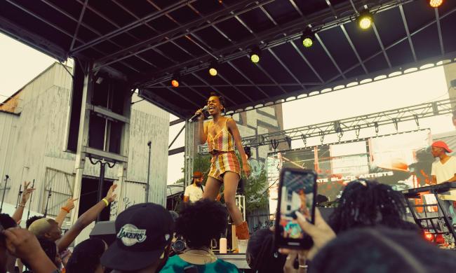 Performer on stage in front of a crowd at TONE Juneteenth Festival.