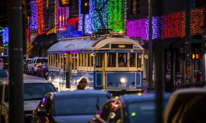 blue trolley going down street during Christmas time with lights in background