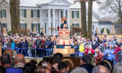 Elvis birthday cake on display in front of Graceland and crowd of people