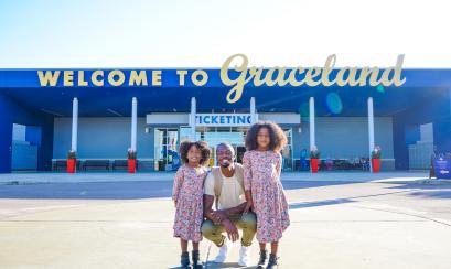 dad poses with daughter in front of welcome to Graceland sign