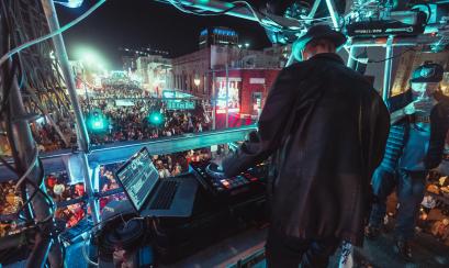 DJ performs on stage on beale street with crowd watching